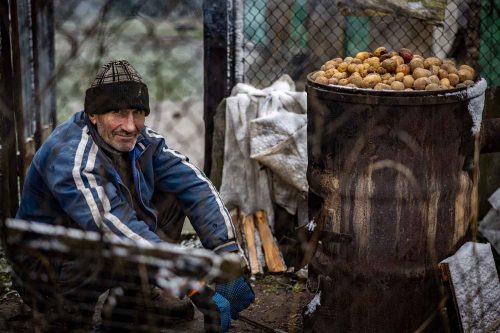 Ukraine Nov 2022,A man warms potatoes outside what remains of his destroyed house. scenes of destruction in the town of Makariv, an hour's drive from Kiev