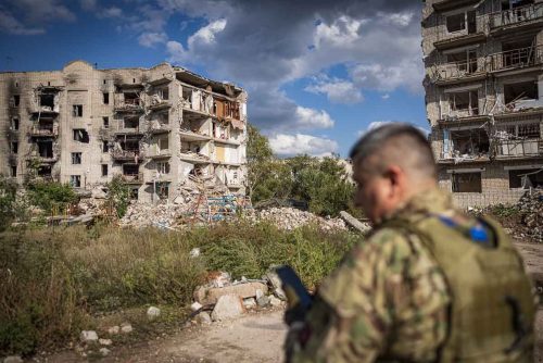 Ukraine, September 2022. Soldiers from the Ukrainian volunteer army walk in front among the ruins of the city of IzyumThe Ukrainian city of Izium (Izyum) is related  with the mass burial site discovered near by. But there are people still living there. Russia heavily bombarded the town. In  September, its forces left the area leaving behind destroyed infrastructure and a population with no food and no water and under shock.
