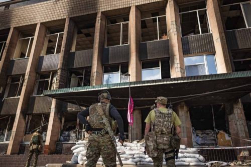 Ukraine, September 2022. Soldiers from the Ukrainian volunteer army walk in front among the ruins of the city of IzyumThe Ukrainian city of Izium (Izyum) is related  with the mass burial site discovered near by. But there are people still living there. Russia heavily bombarded the town. In  September, its forces left the area leaving behind destroyed infrastructure and a population with no food and no water and under shock.
