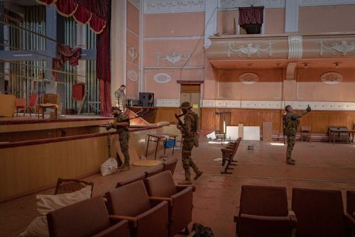 Ukraine, September 2022. A team of the Ukranian volunteer army visits the interior of the house of culture in Izyum where the Russians had installed their central command for months of occupation. After their rapid retreat, the Ukranian soldiers find numerous remains of the Russian staySoldiers from the Ukrainian volunteer army walk in front among the ruins of the city of IzyumThe Ukrainian city of Izium (Izyum) is related  with the mass burial site discovered near by. But there are people still living there. Russia heavily bombarded the town. In  September, its forces left the area leaving behind destroyed infrastructure and a population with no food and no water and under shock.