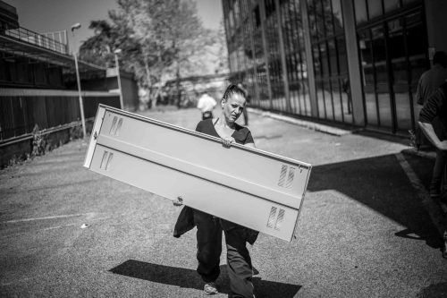 Rome, Italy, apr,2014.A woman is carring a metal door in order to block the entrance of the building they just have occupied. A group of homeless from both Italian and non-EU countries occupy an abandoned building that up to nine months ago belong to the offices of the National Social Security Institute (INPS).Un gruppo di senza casa sia italiani che provenienti da paesi extracomunitari occupano un edificio abbandonato che fino a 9 mesi fa era la sede di uffici dell Istituto Nazionale della Previdenza Sociale (INPS).